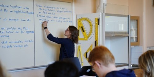 A teacher writing on a whiteboard