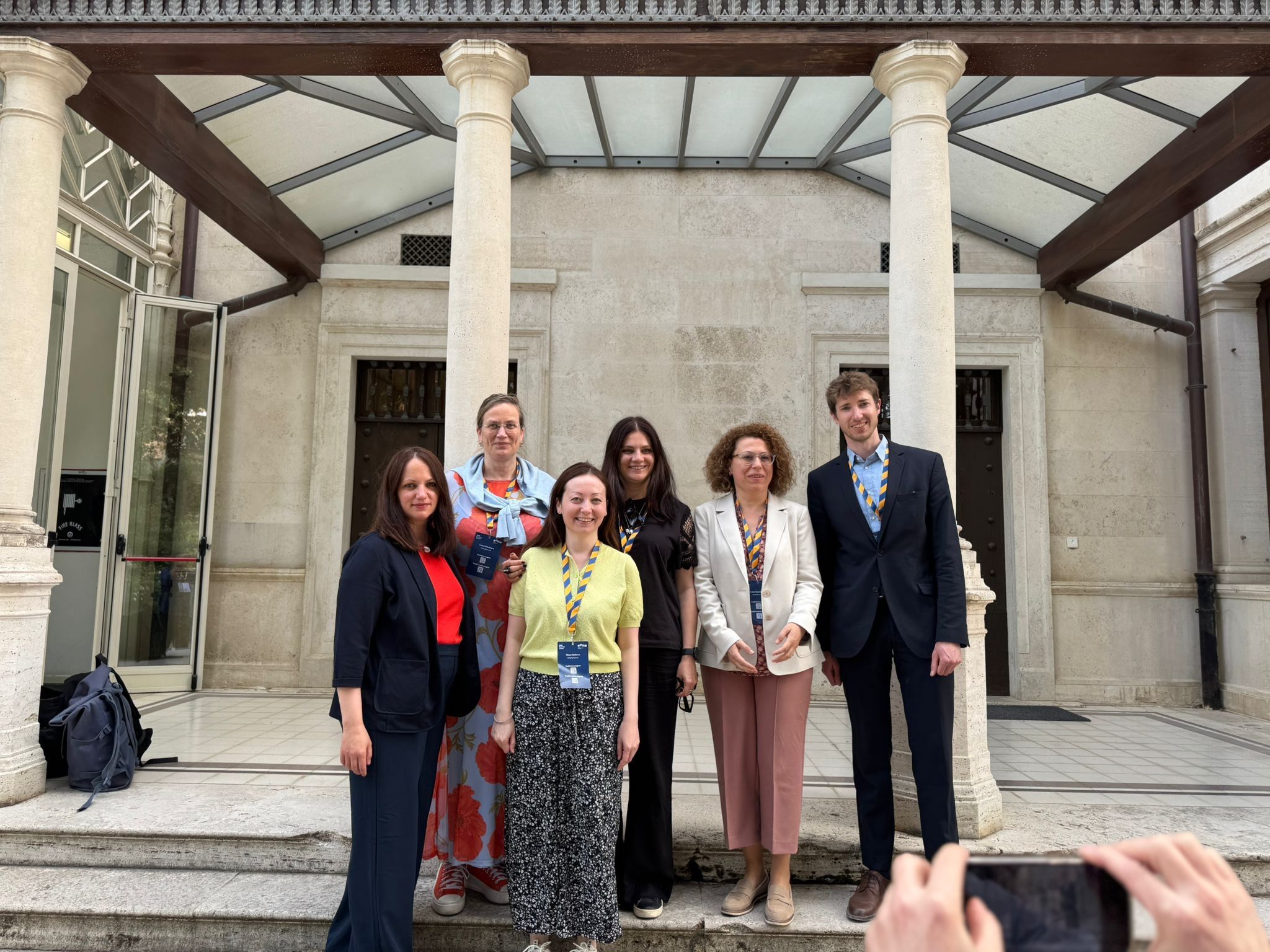 Group photo of six EMMA board members standing outside a historic building with stone columns and a glass awning.