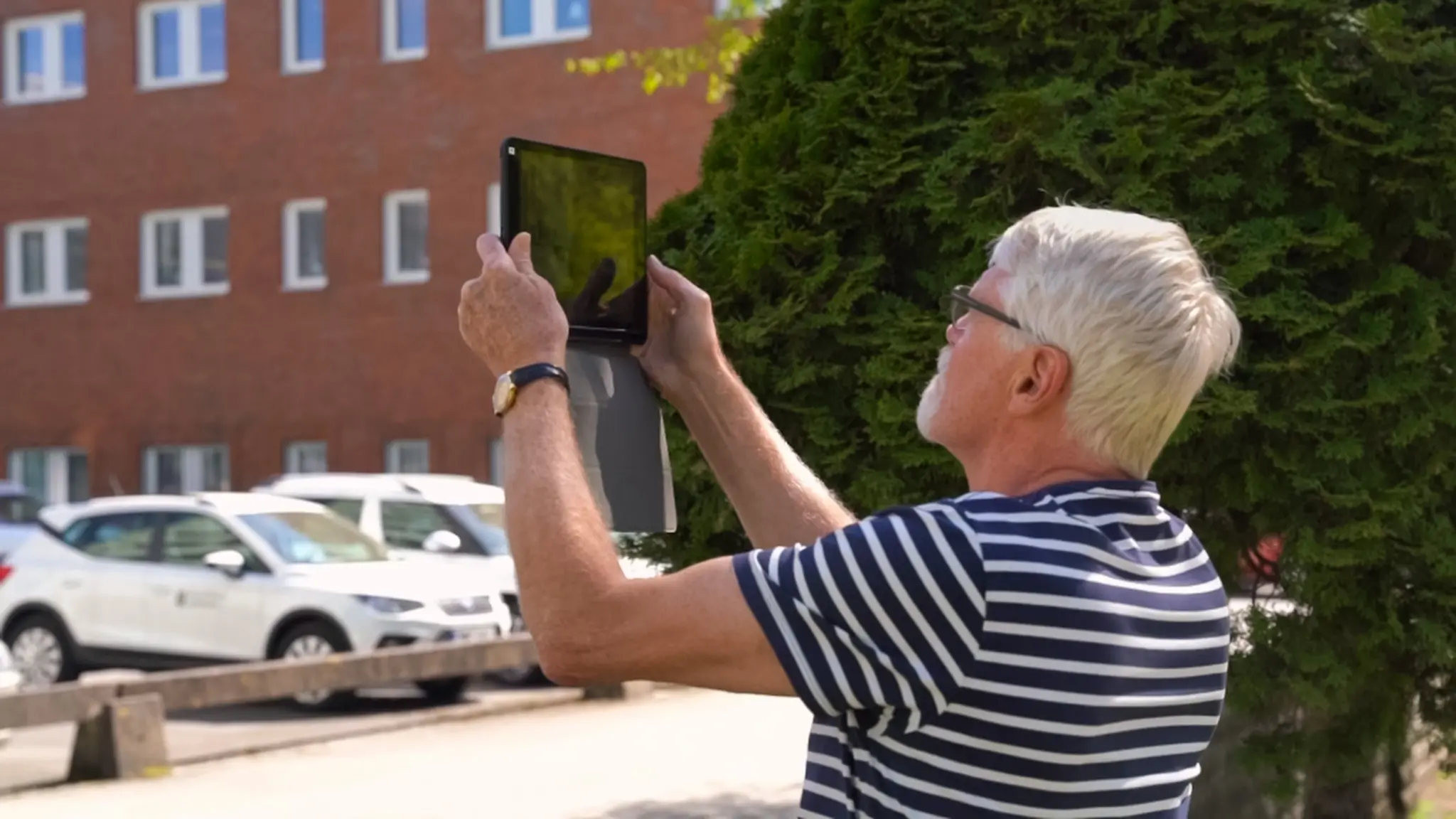 En äldre man fotar stadsmiljö med en Ipad