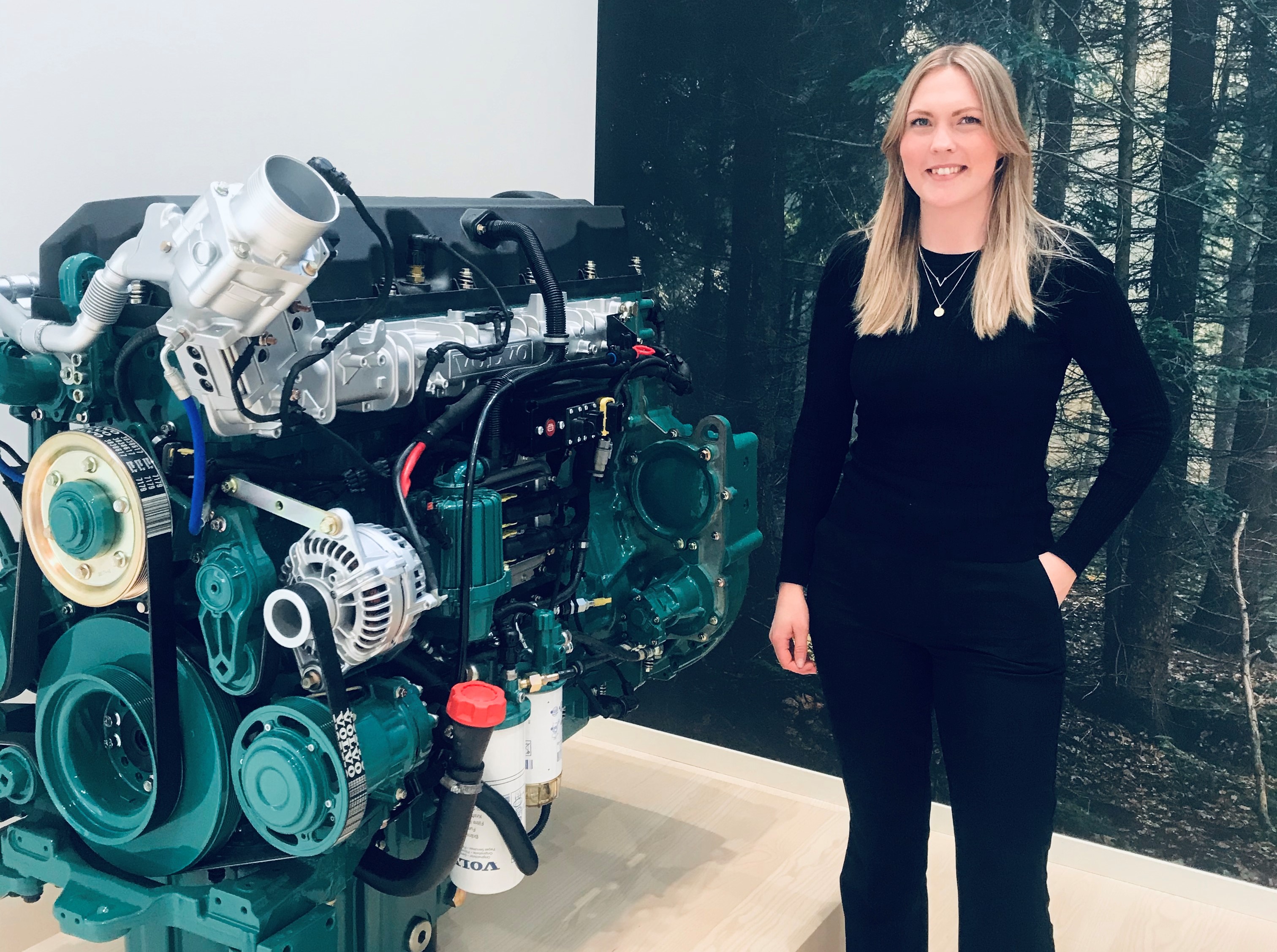 Picture of the former JTH student Victoria Andersson standing next to an engine.