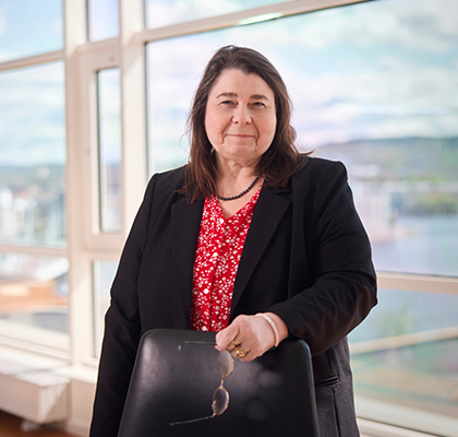 Catherine Legrand står inne i ett kontor och ler mot kameran med sina glasögon i handen.