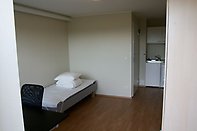 Student dorm room with bed, desk and bookshelf